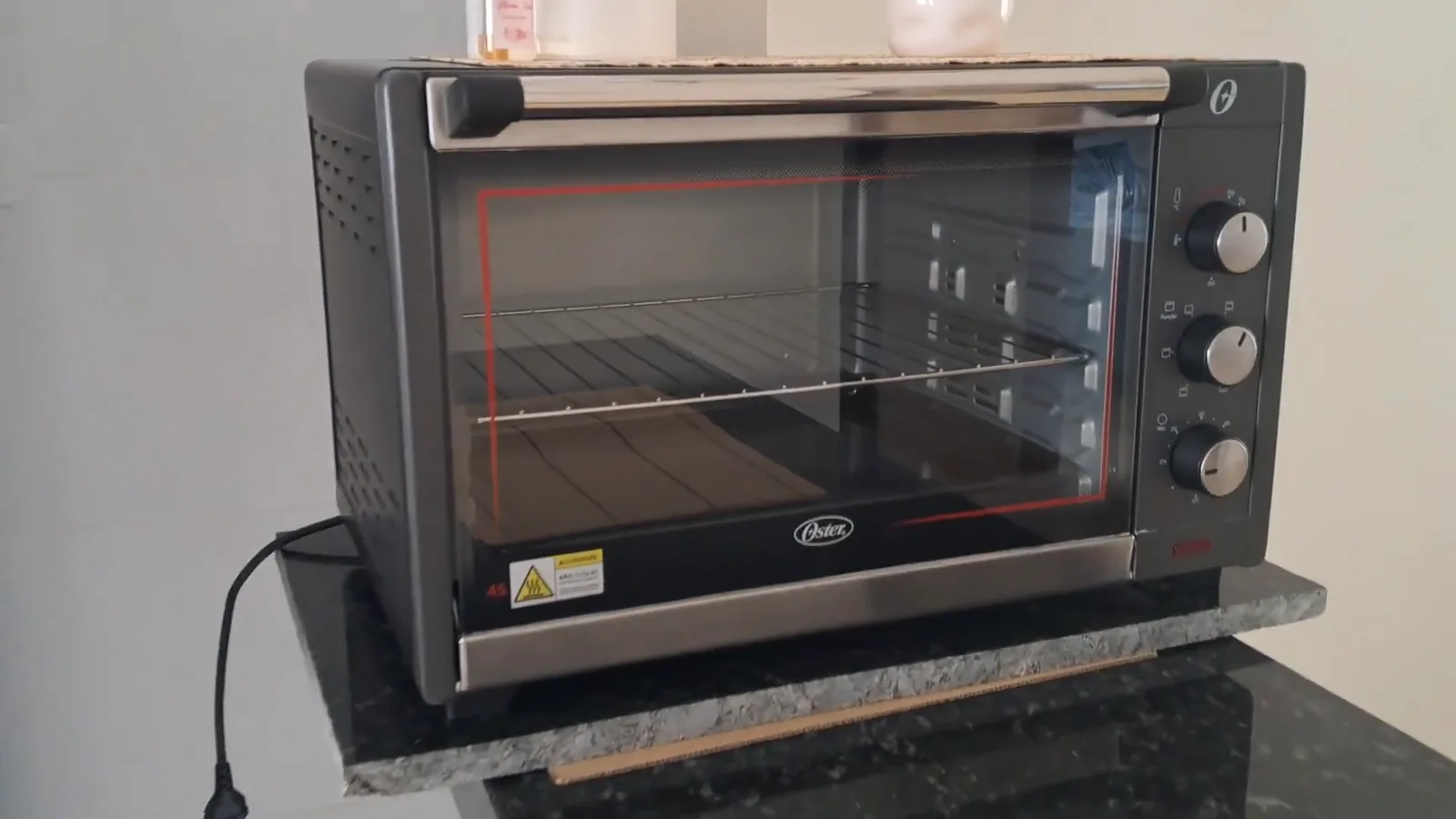 Forno elétrico de bancada Oster instalado sobre bancada na cozinha