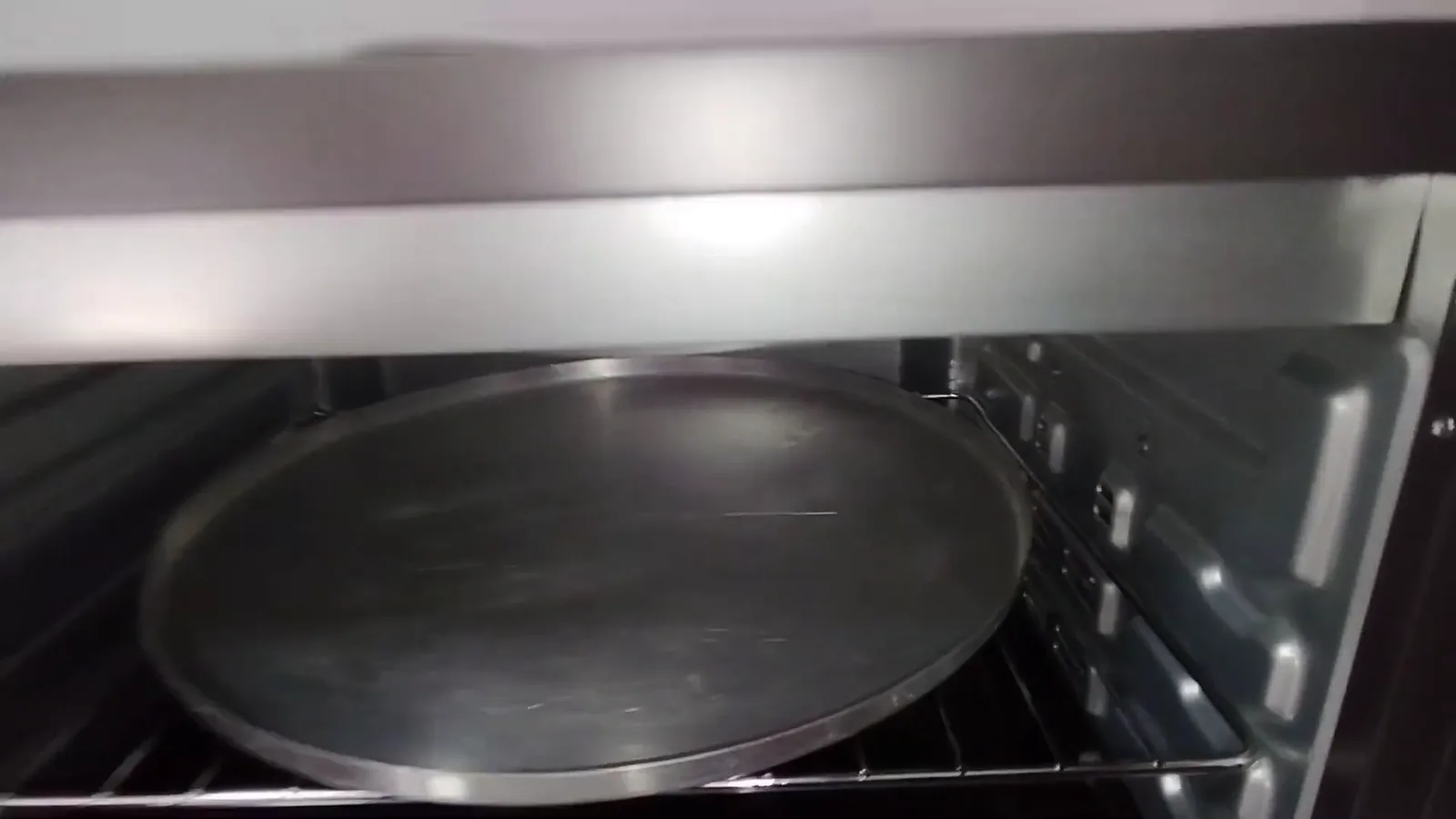 Assadeira redonda de pizza posicionada dentro do forno Oster 45L