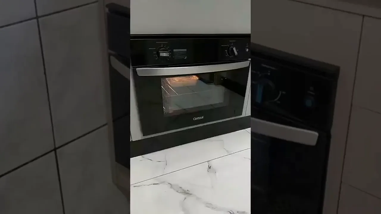 Forno elétrico de embutir Consul assando prato com iluminação interna acesa