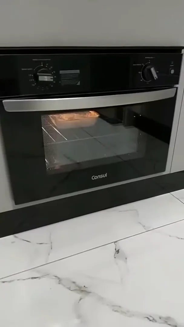 Forno elétrico Consul em funcionamento assando alimento em cozinha planejada