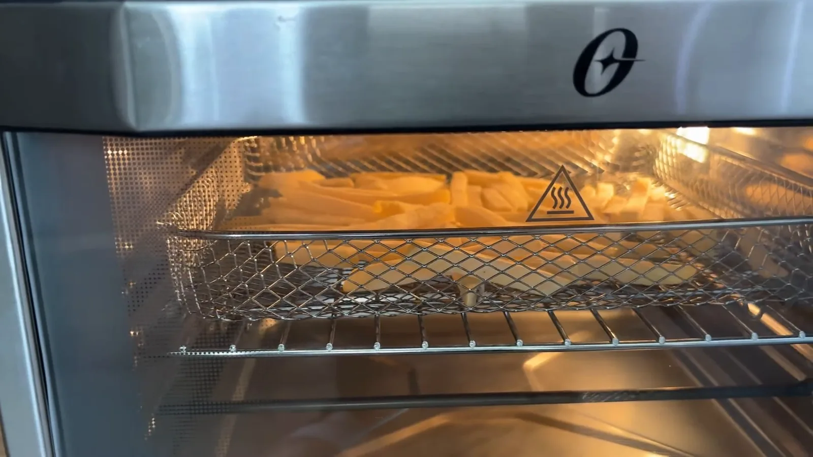 Batatas fritando no cesto sob a resistência do forno elétrico