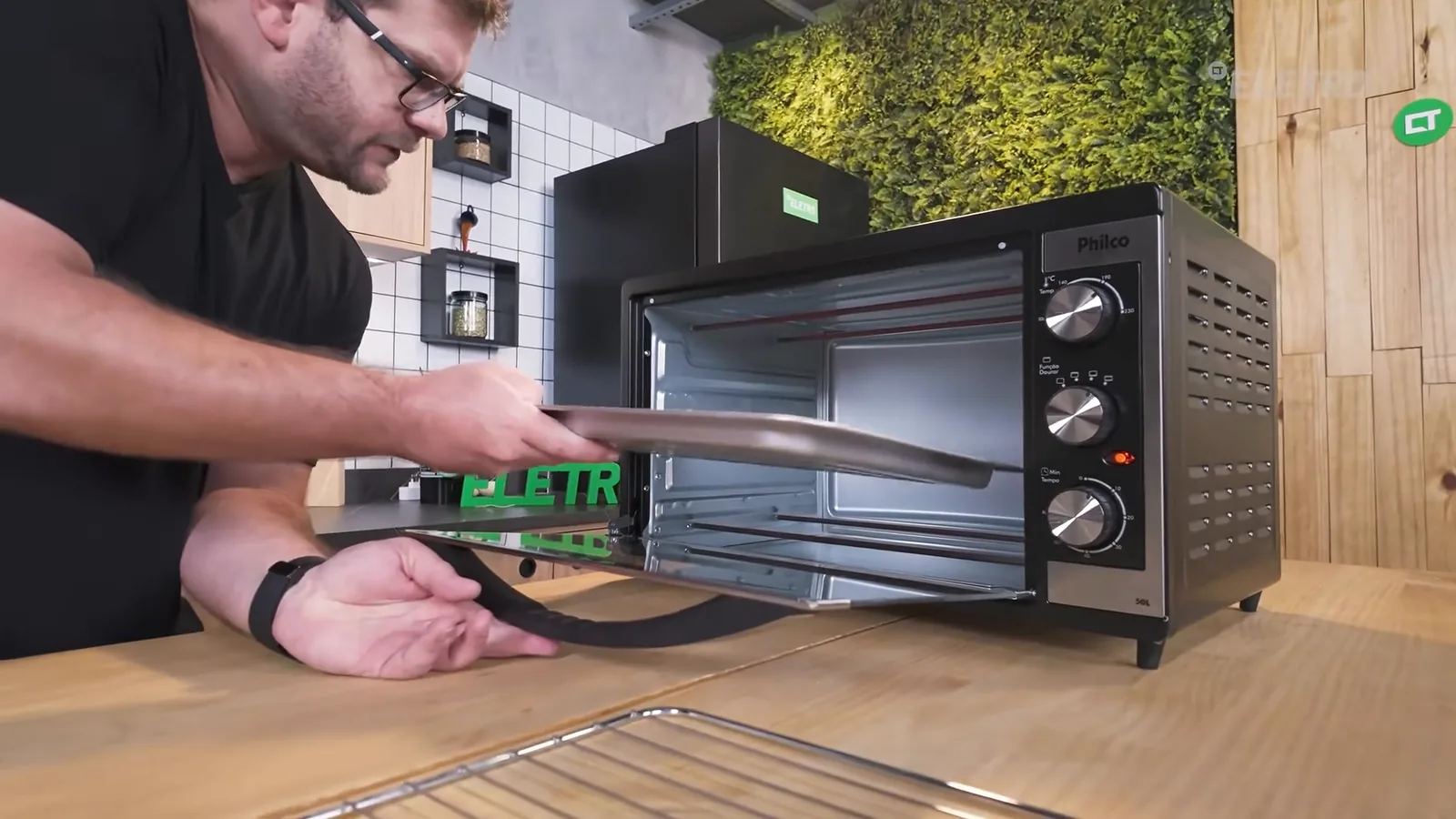 Assadeira com pizza sendo colocada no forno elétrico para assar