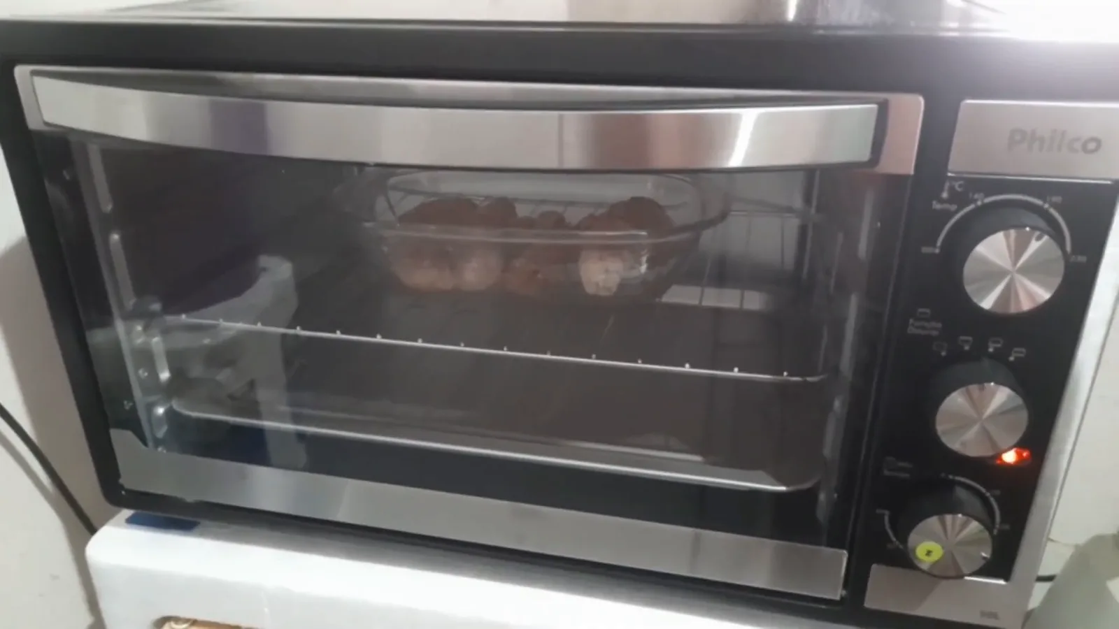 Forno elétrico assando carne em refratário de vidro sobre a grelha