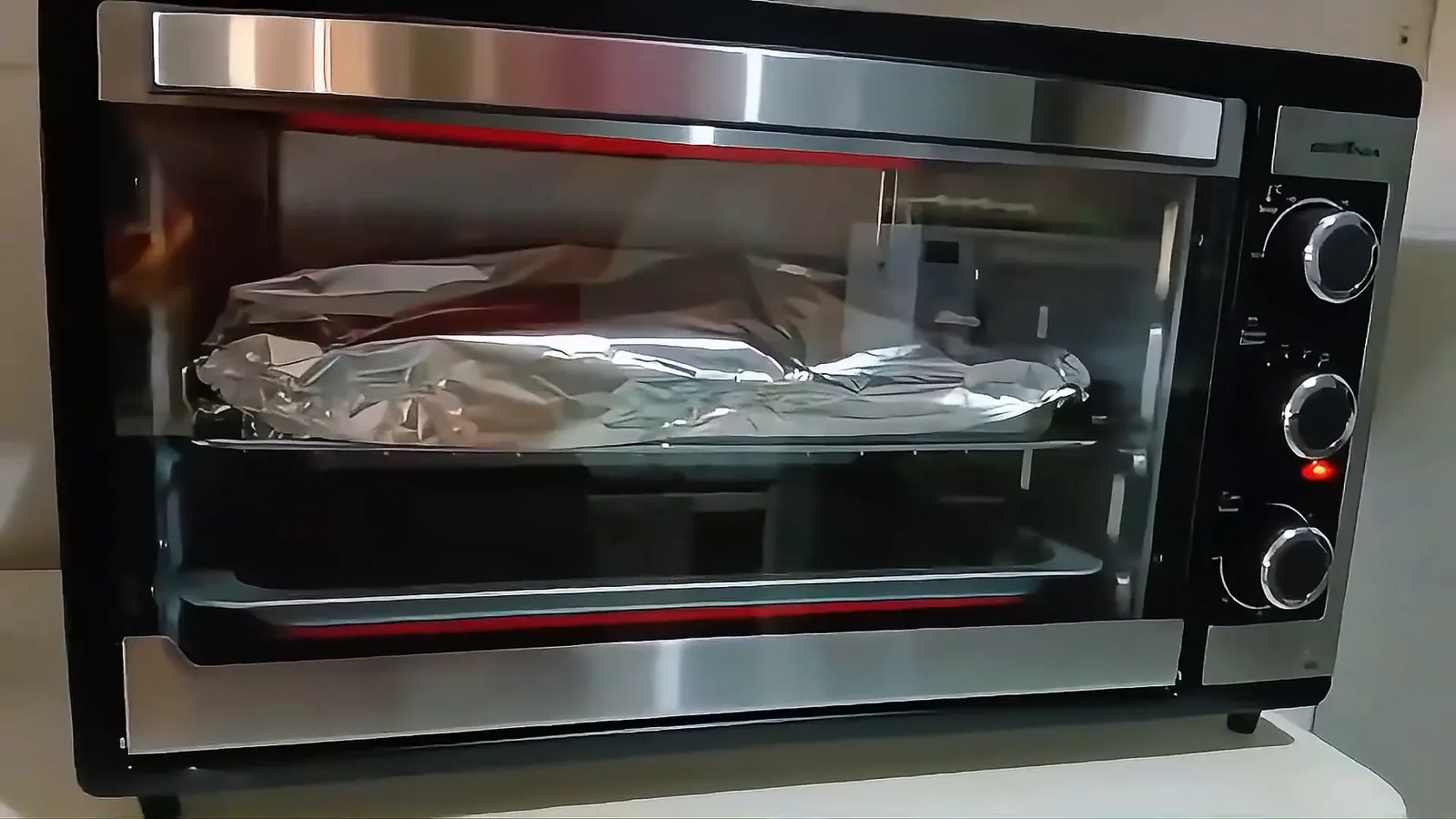 Forno elétrico Britânia assando alimento com resistência superior em funcionamento