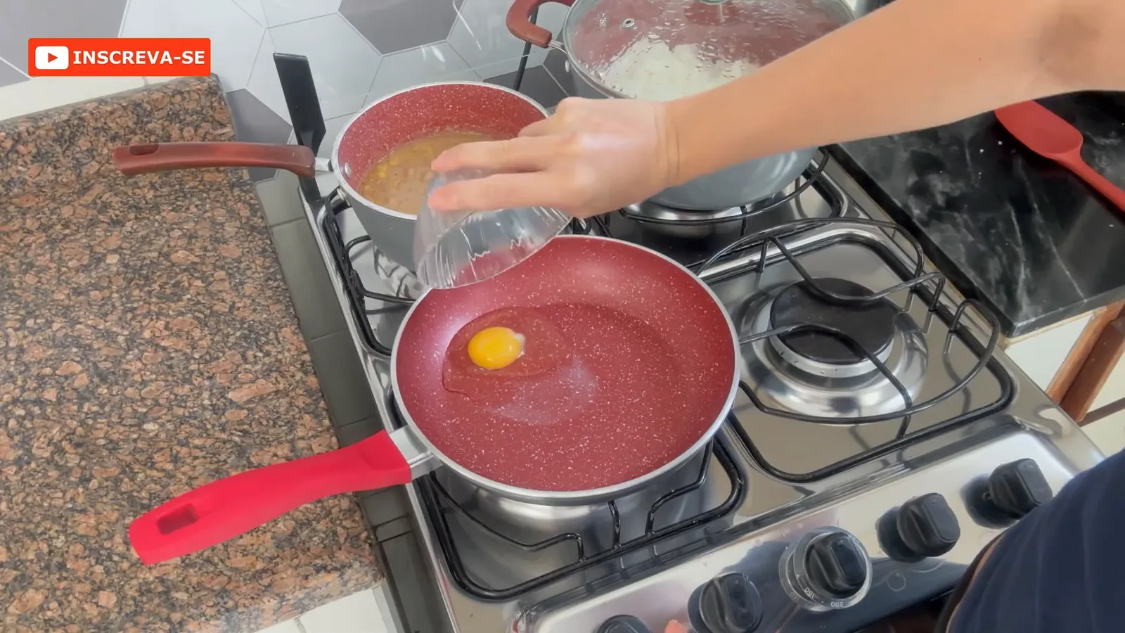 Ovo sendo despejado na frigideira antiaderente Philco Redstone sobre o fogão