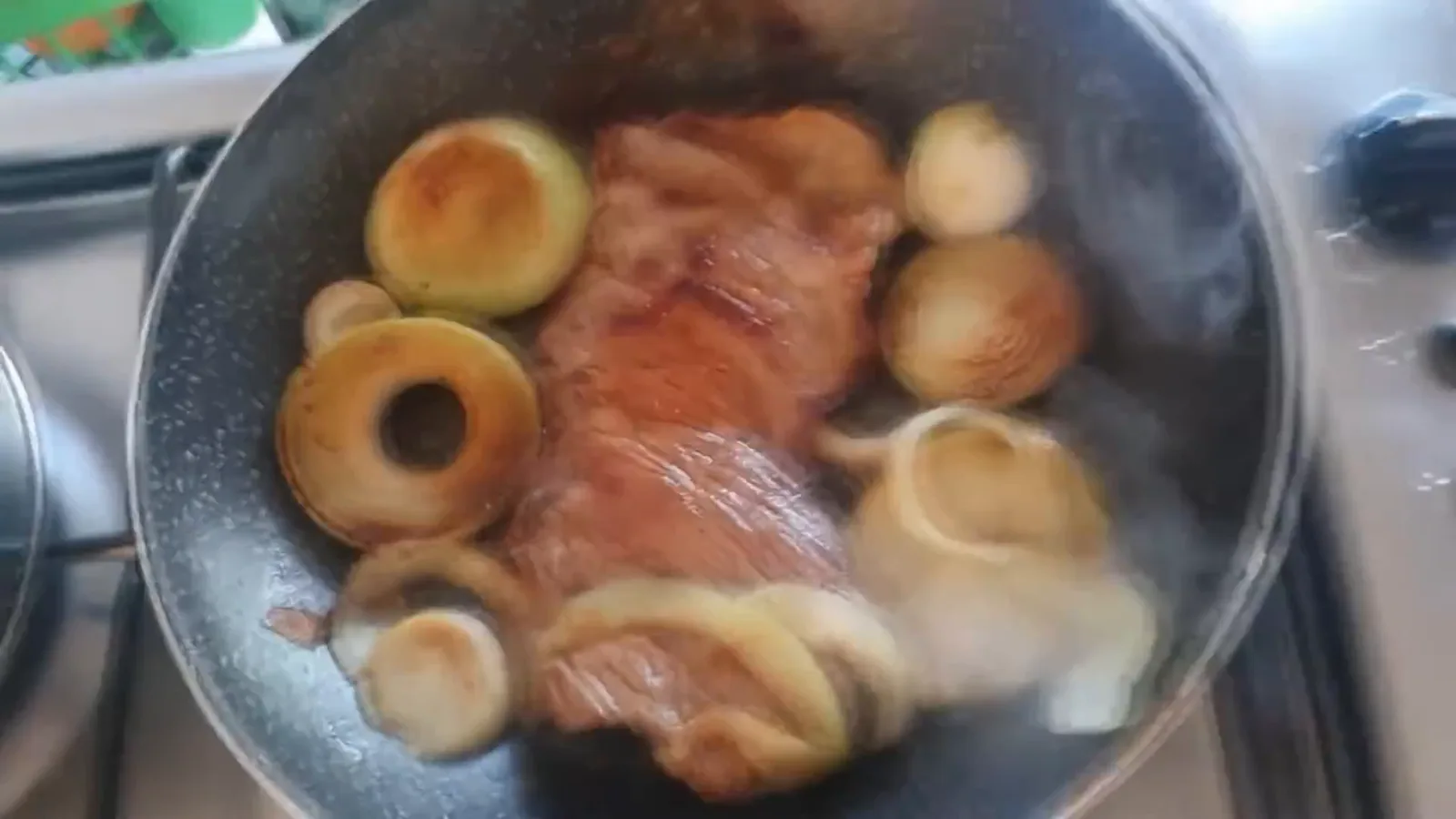 Carne e cebolas fritando sem óleo na frigideira antiaderente Rochedo