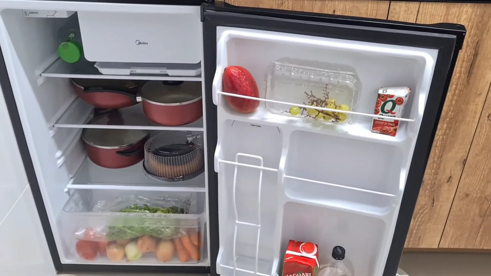 Espaço interno do frigobar abastecido com diversos alimentos e bebidas