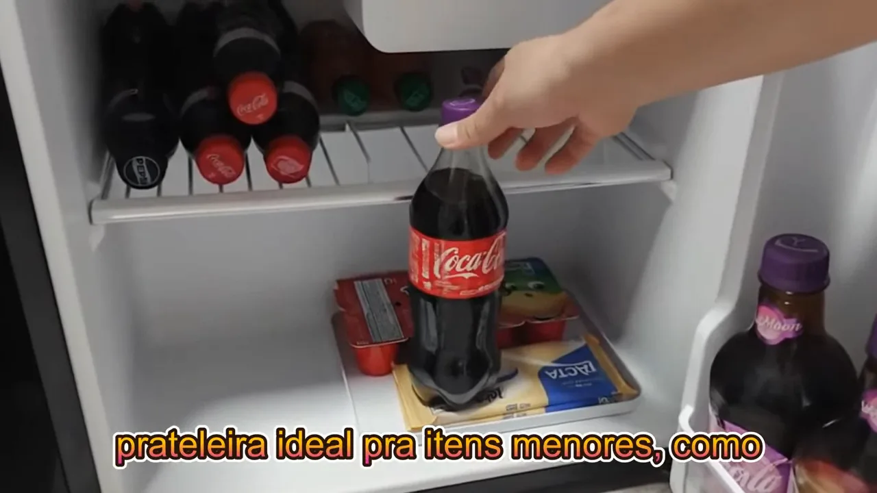 Inserção de garrafa de refrigerante na prateleira interna do frigobar