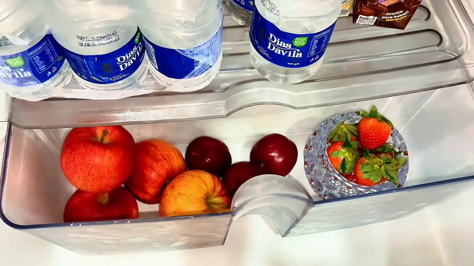 Gaveta de frutas aberta com maçãs e morangos frescos armazenados