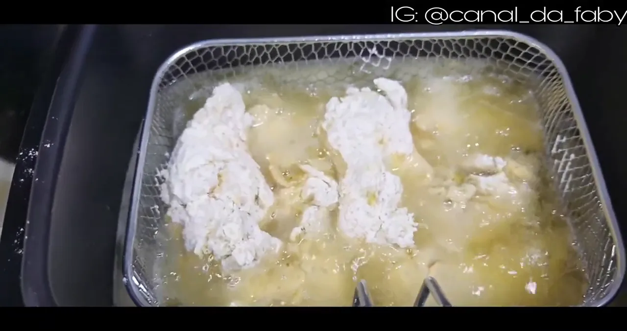 Frango empanado fritando sob imersão no cesto da fritadeira Mondial