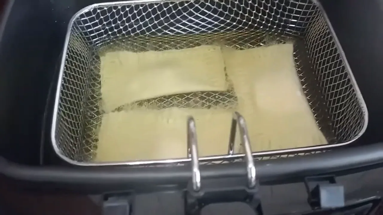 Pastéis sendo imersos no óleo quente na fritadeira Mondial Big Fry