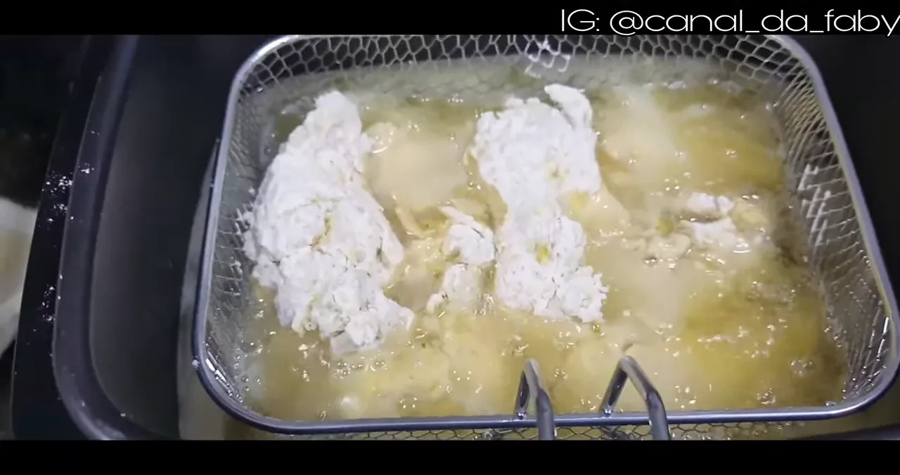 Frango empanado fritando no óleo quente dentro da fritadeira elétrica