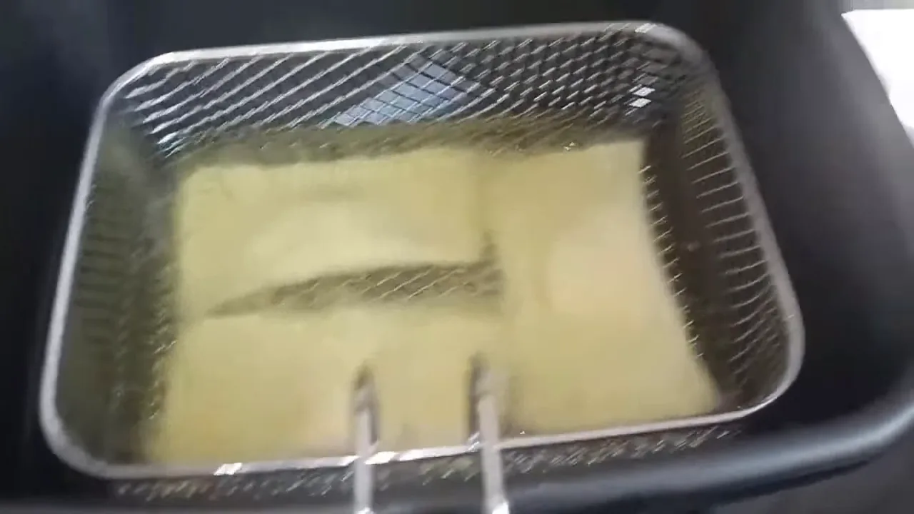 Cesto com pastéis sendo imerso no óleo quente da fritadeira