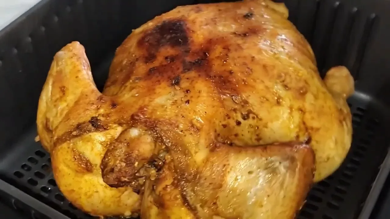 Frango inteiro assado dourado dentro do cesto da air fryer