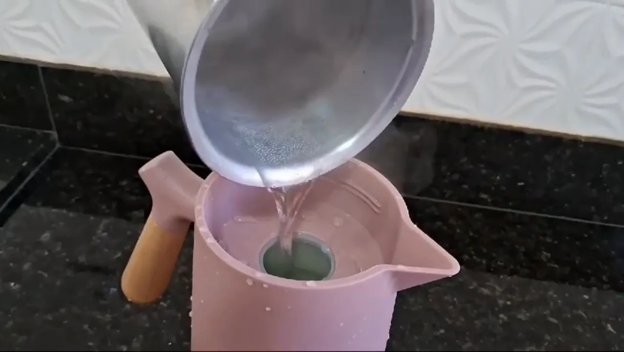 Água quente sendo colocada para escaldar a garrafa térmica Wolff