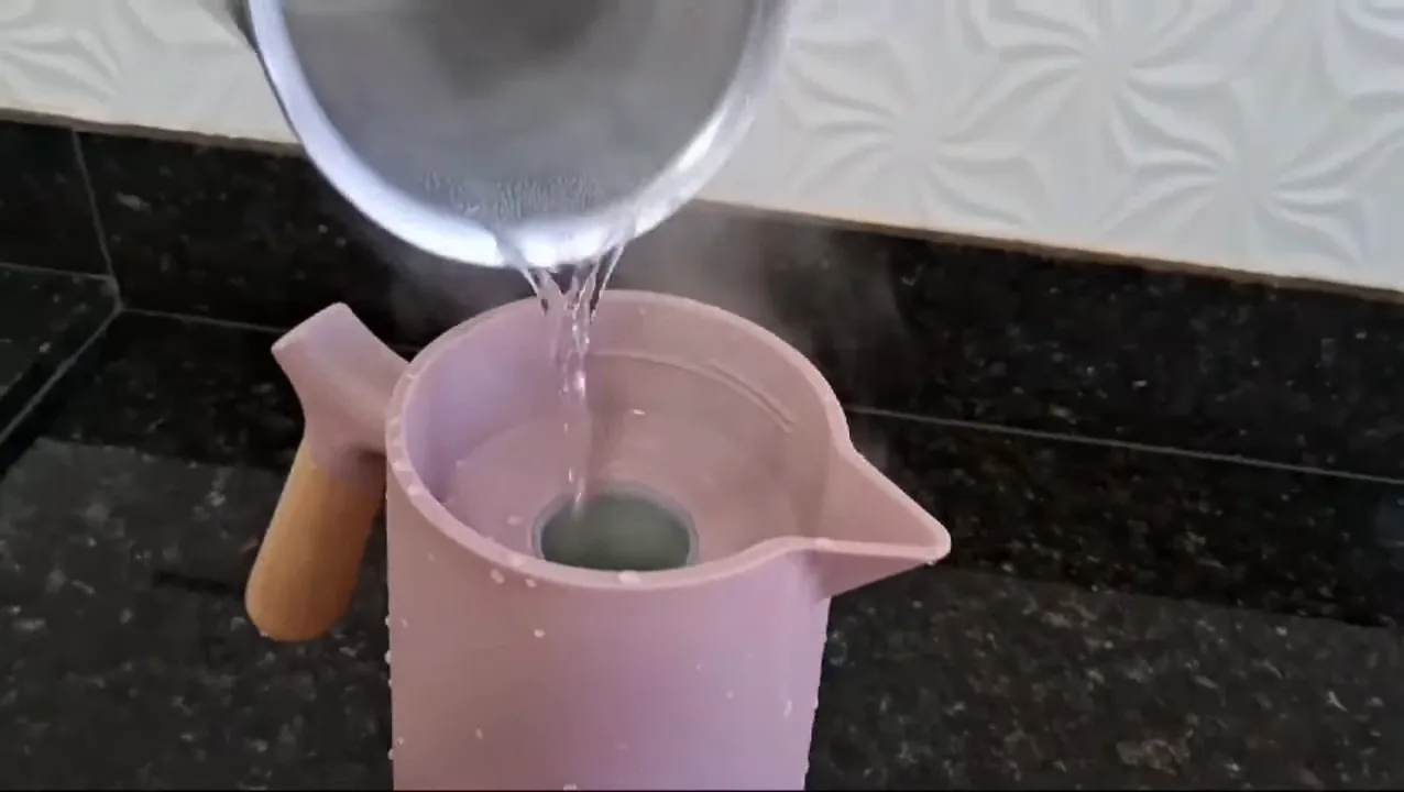 Despejando água fervente para escaldar a garrafa térmica Wolff