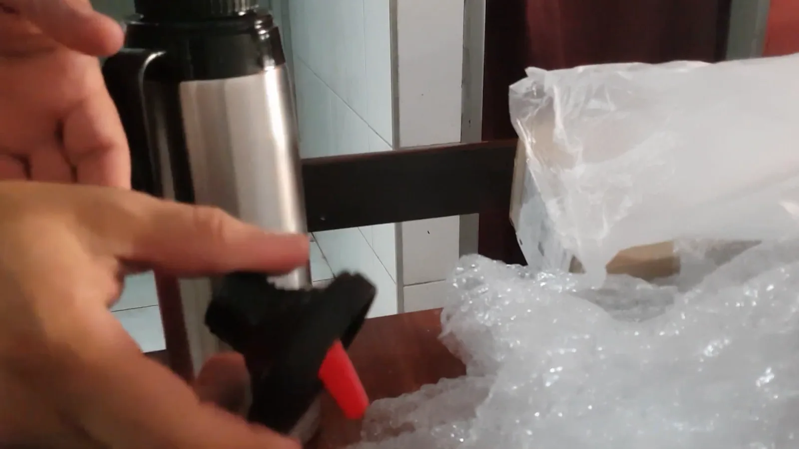 Tampa com rolha dosadora da garrafa térmica de inox sendo operada