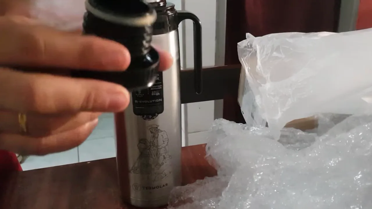 Rosqueando a tampa da garrafa térmica de inox Termolar na mesa