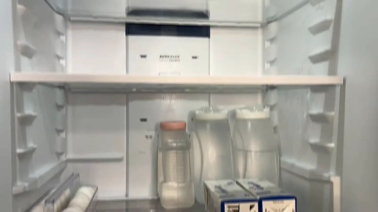 Interior do refrigerador amplo com prateleiras de vidro bem iluminadas