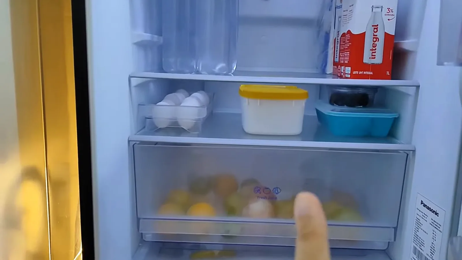 Prateleiras internas do refrigerador organizadas com alimentos e garrafas
