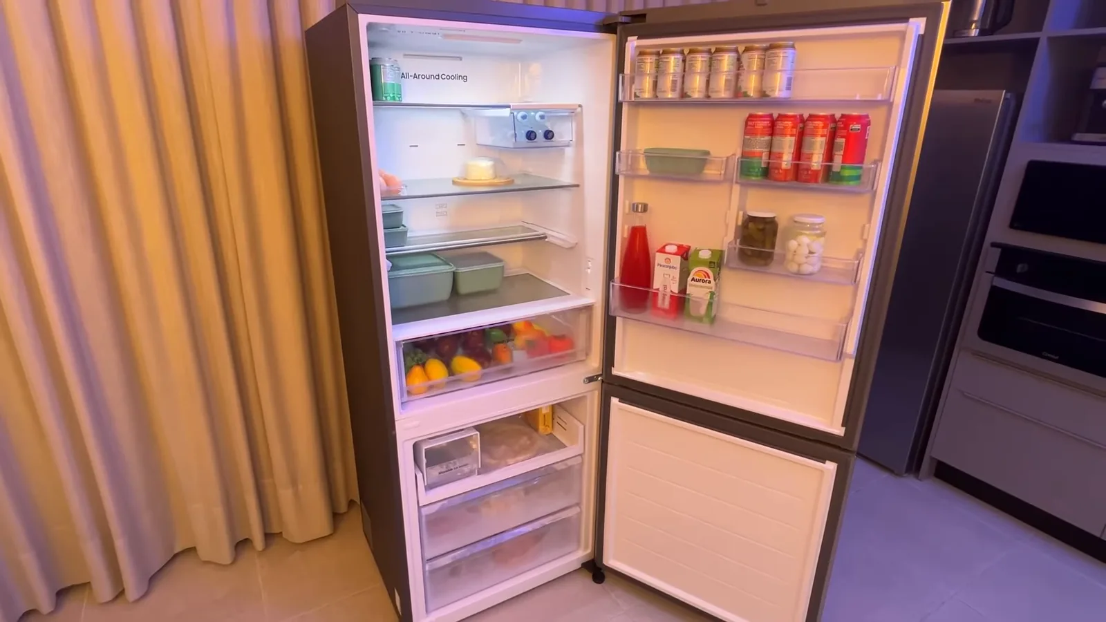 Refrigerador inverse aberto exibindo compartimentos internos organizados e iluminados