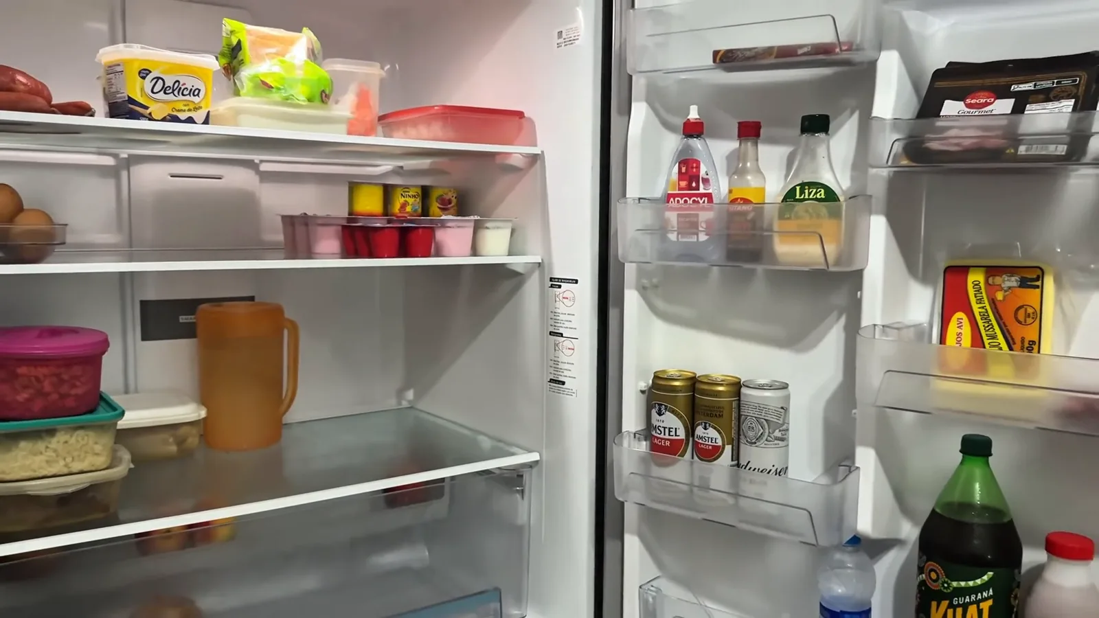 Interior espaçoso do refrigerador iluminado por LED com alimentos organizados
