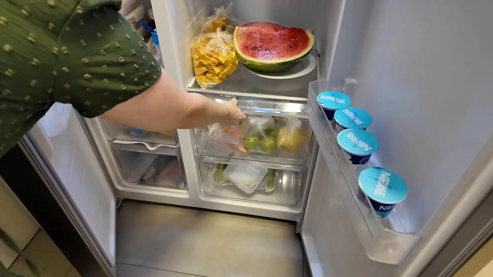 Gaveta inferior para legumes aberta no compartimento refrigerador da geladeira