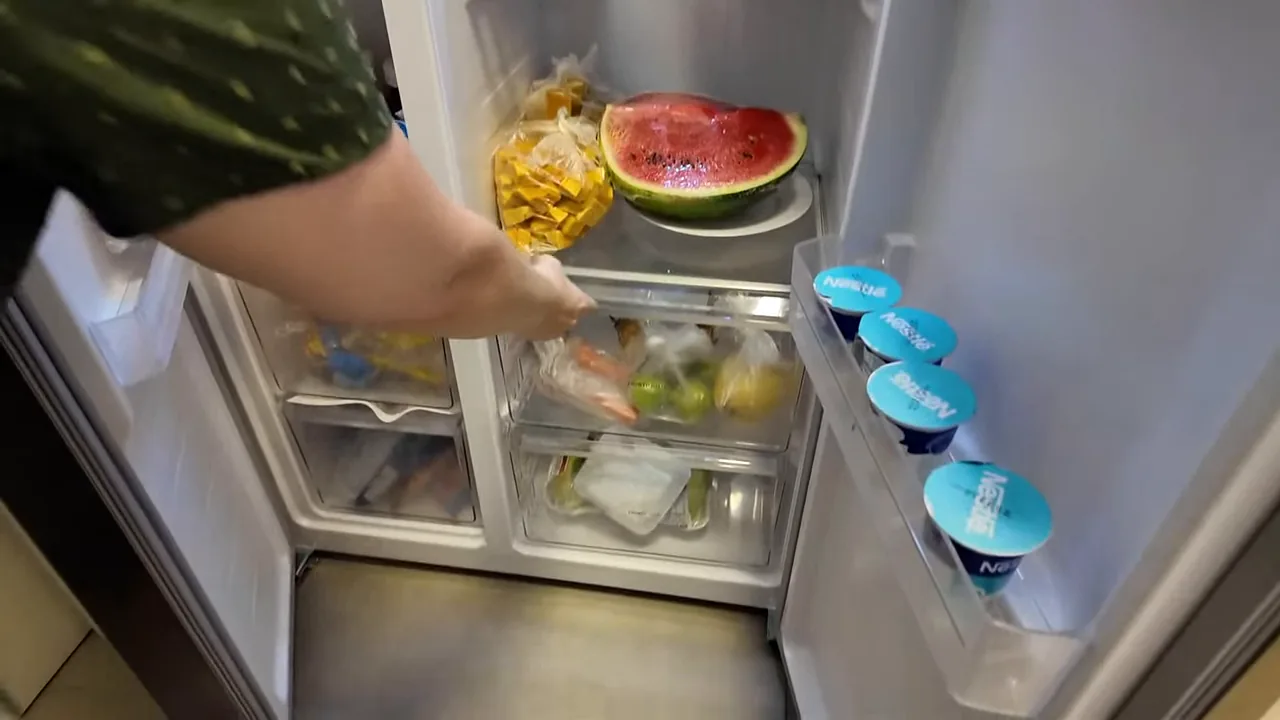 Gaveta de legumes da geladeira sendo aberta no compartimento refrigerador