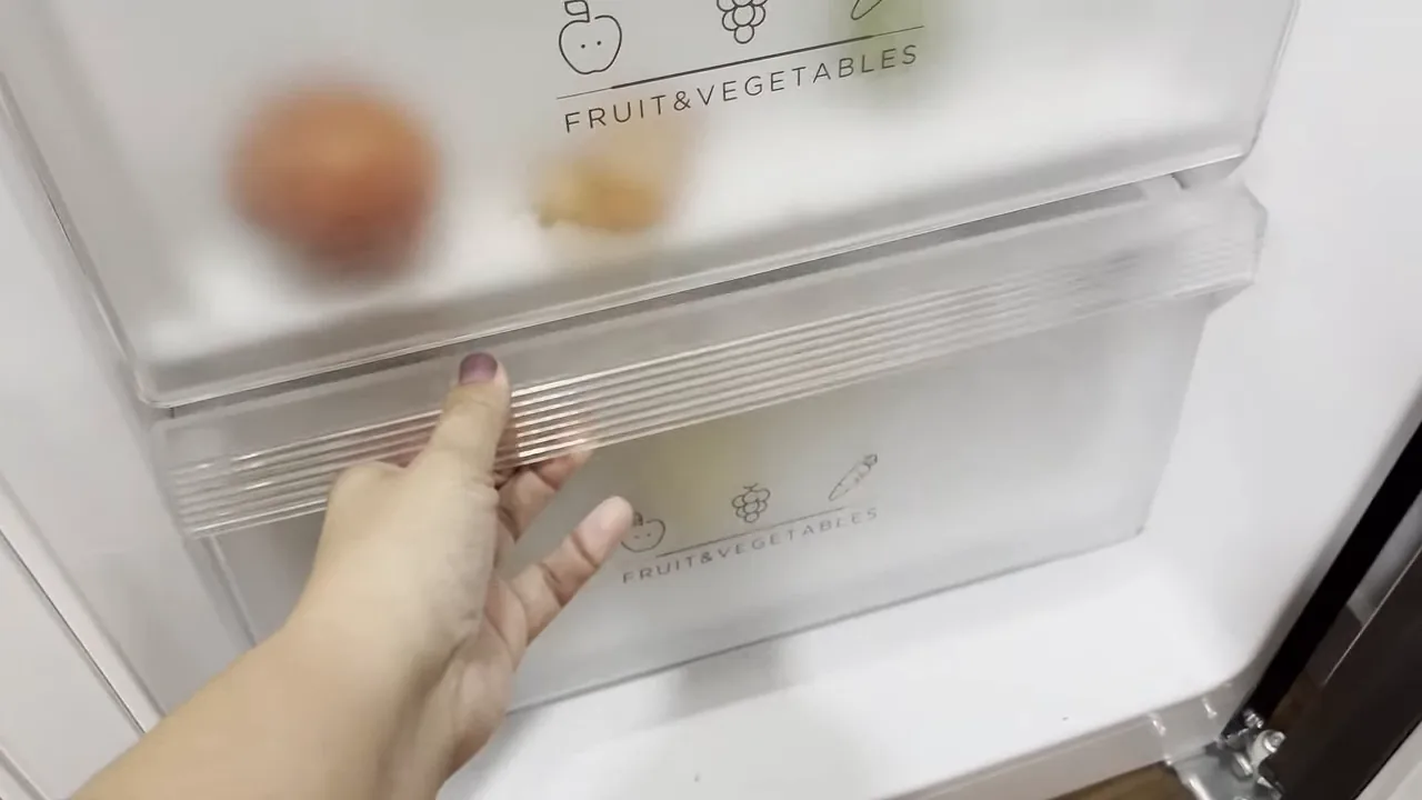 Gaveta de frutas e legumes sendo aberta no refrigerador
