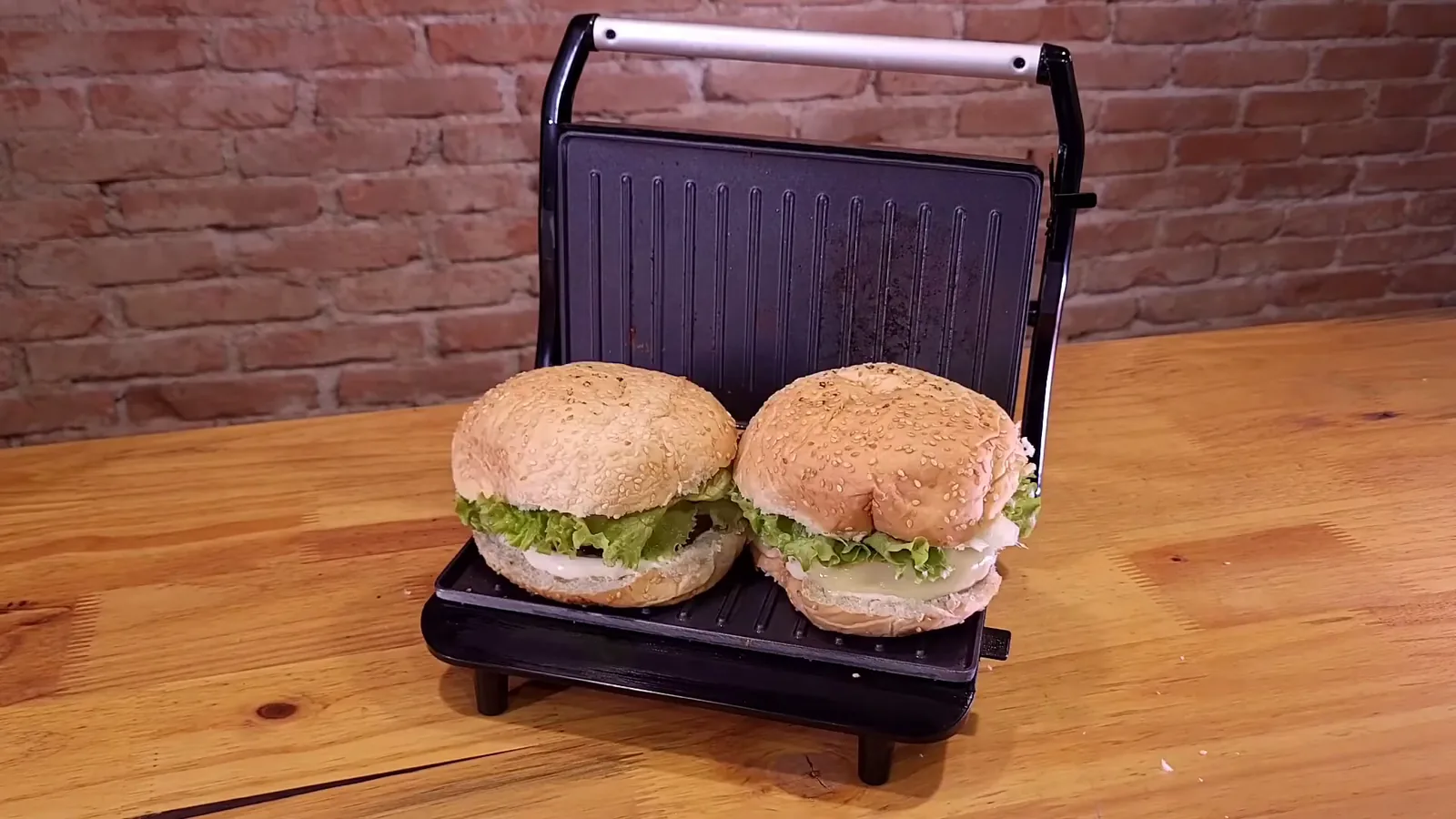 Chapa articulada do grill Mondial prensando sanduíches altos na bancada