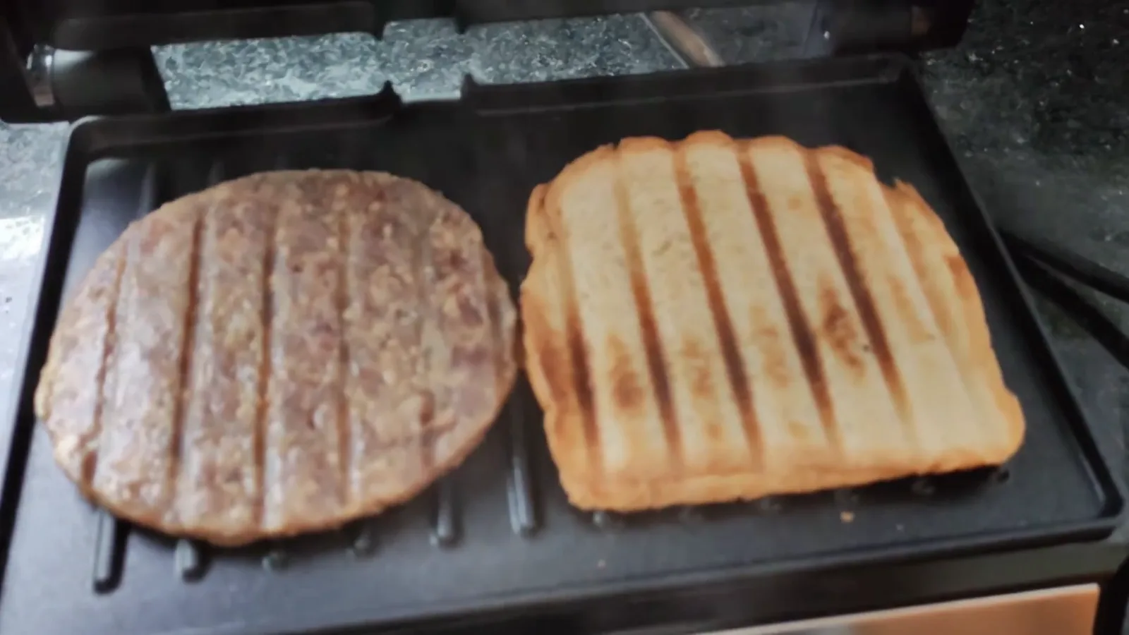 Grill elétrico aberto tostando pão de forma e hambúrguer