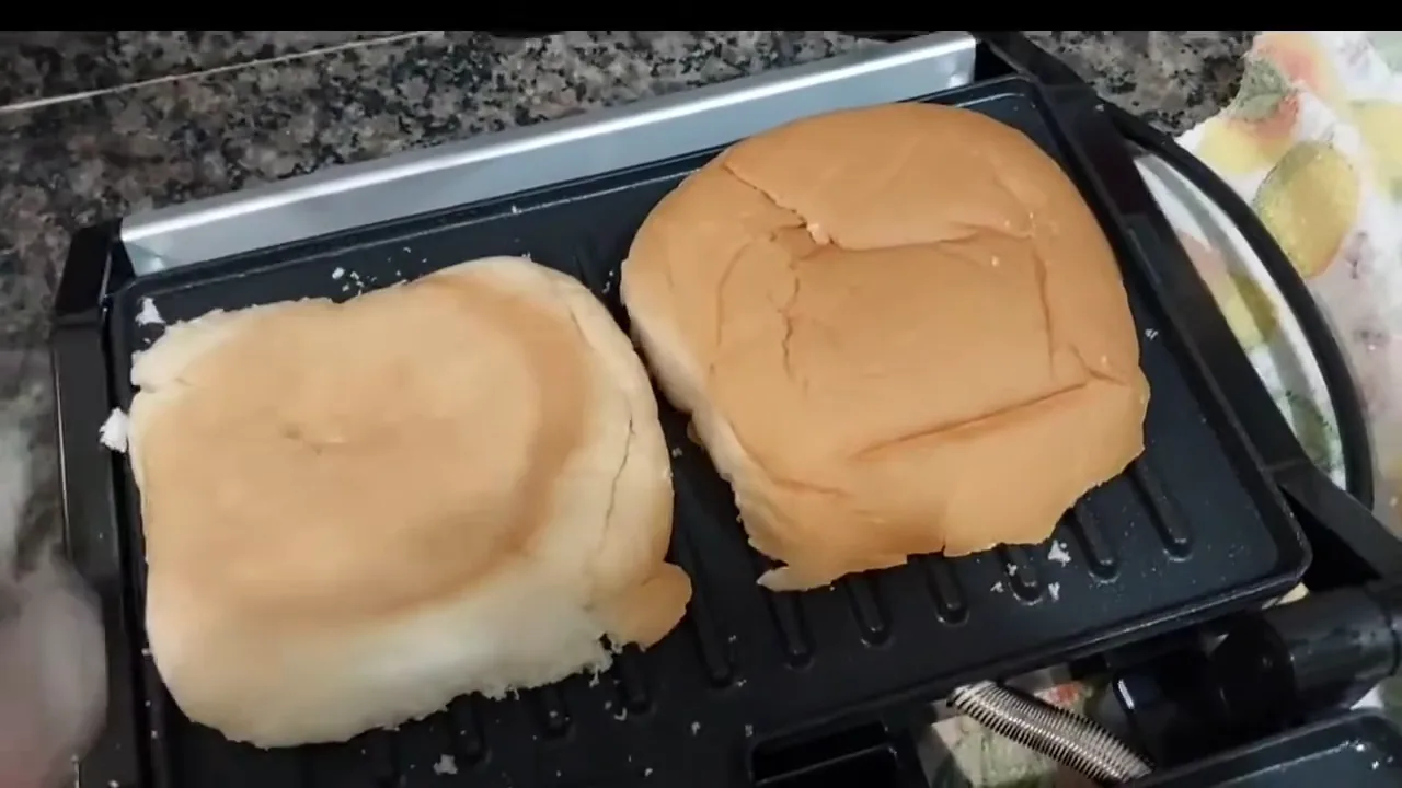 Grill elétrico aberto em 180 graus tostando pães e hambúrguer simultaneamente