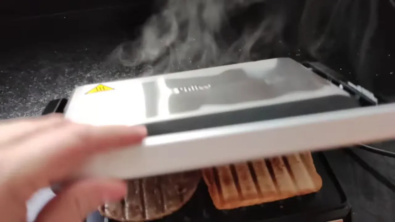 Abertura do grill elétrico revelando pão tostado e hambúrguer grelhado