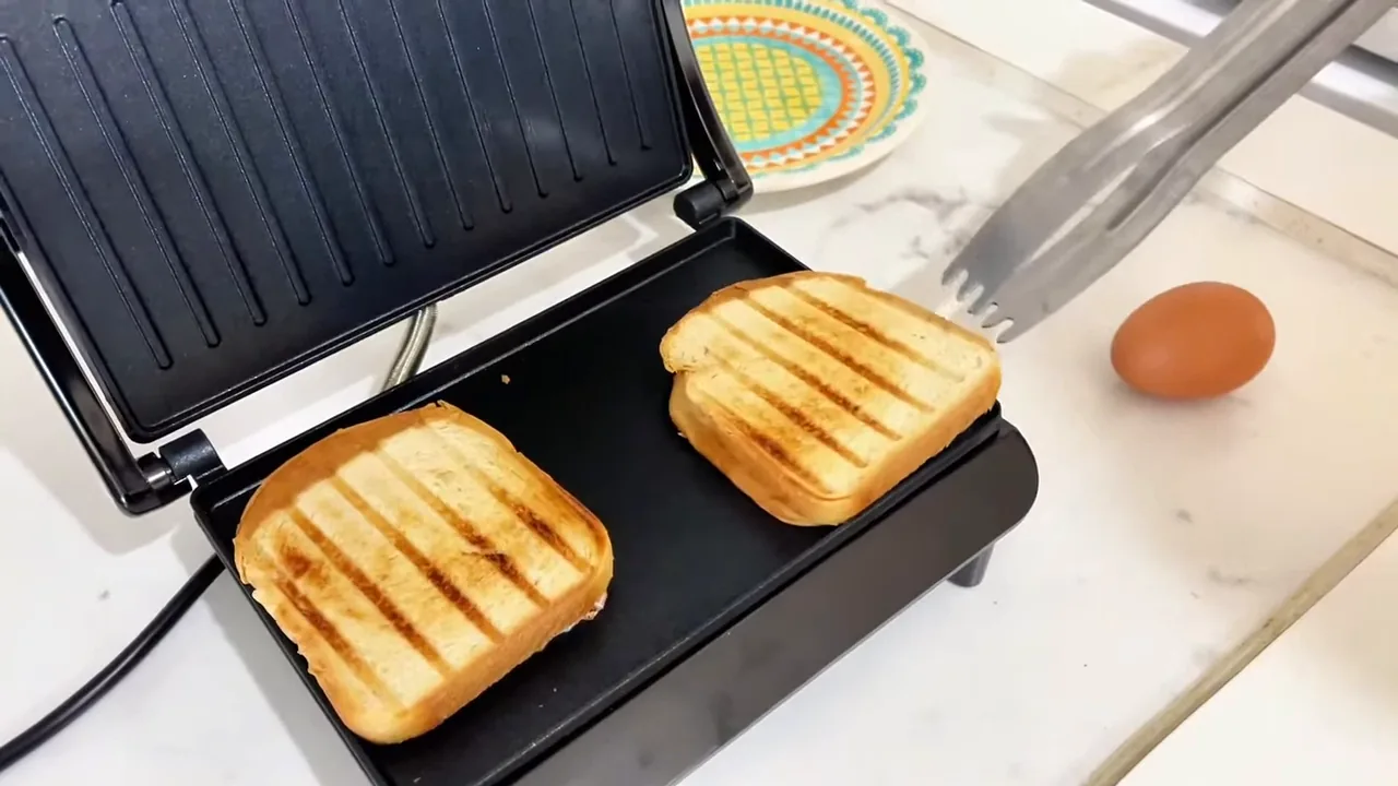Retirada de sanduíches tostados das chapas do grill elétrico