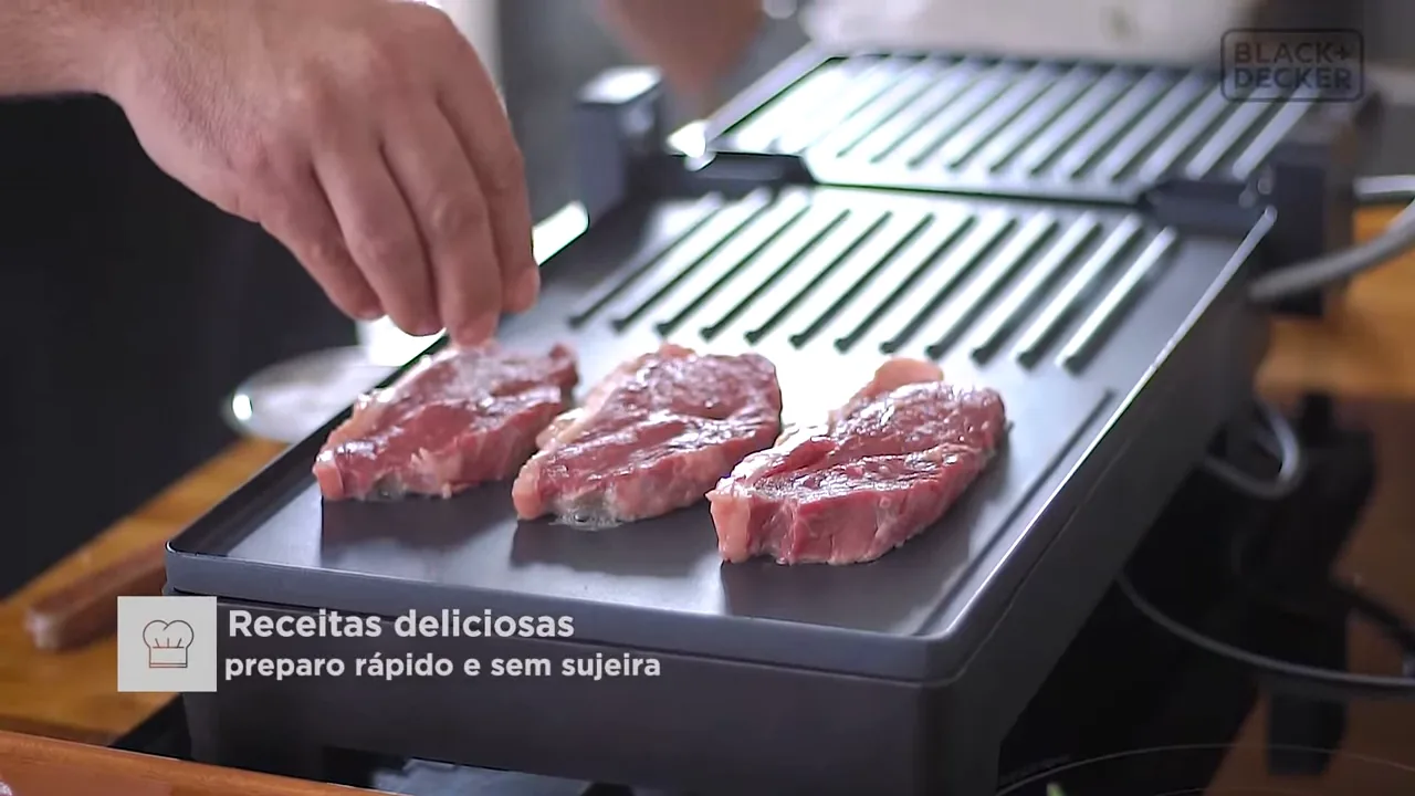 Temperando bifes de carne na chapa aquecida do grill elétrico