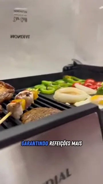 Carnes e vegetais assando sobre as chapas do grill elétrico