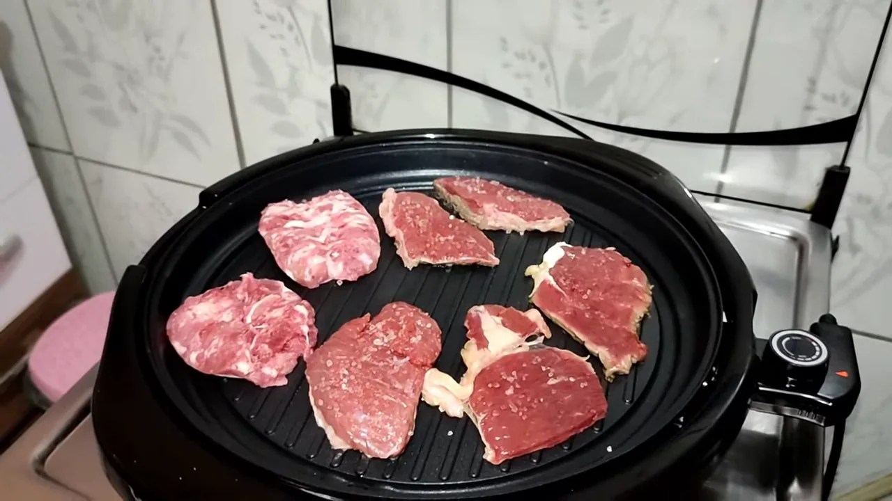 Carnes grelhando uniformemente sobre a ampla chapa antiaderente do aparelho