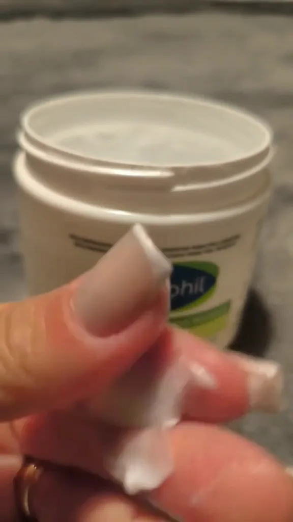 Textura densa e consistente do creme hidratante Cetaphil nos dedos