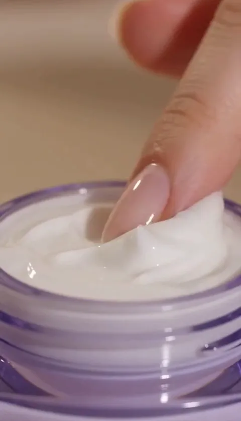 Dedo retirando uma porção do creme facial antissinais Renew