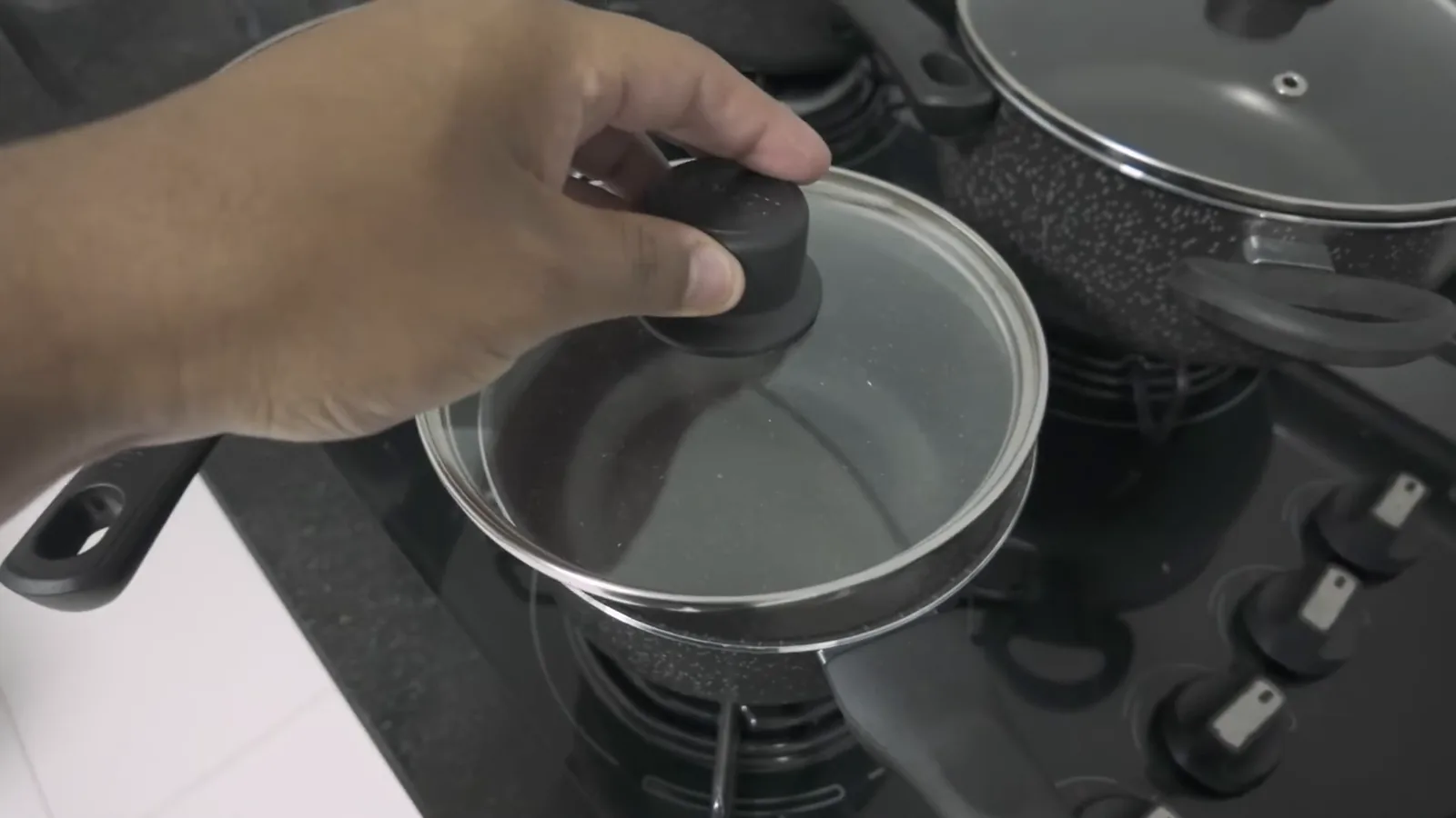 Panela com tampa de vidro transparente sobre a boca do fogão