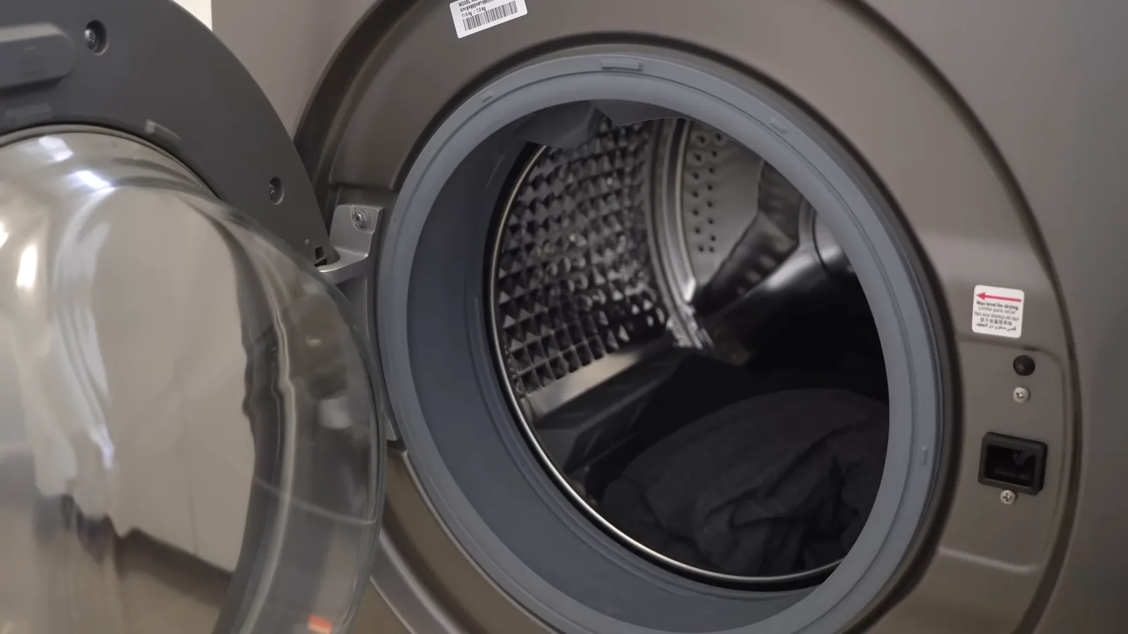 Colocando roupas dentro do tambor da lava e seca Samsung