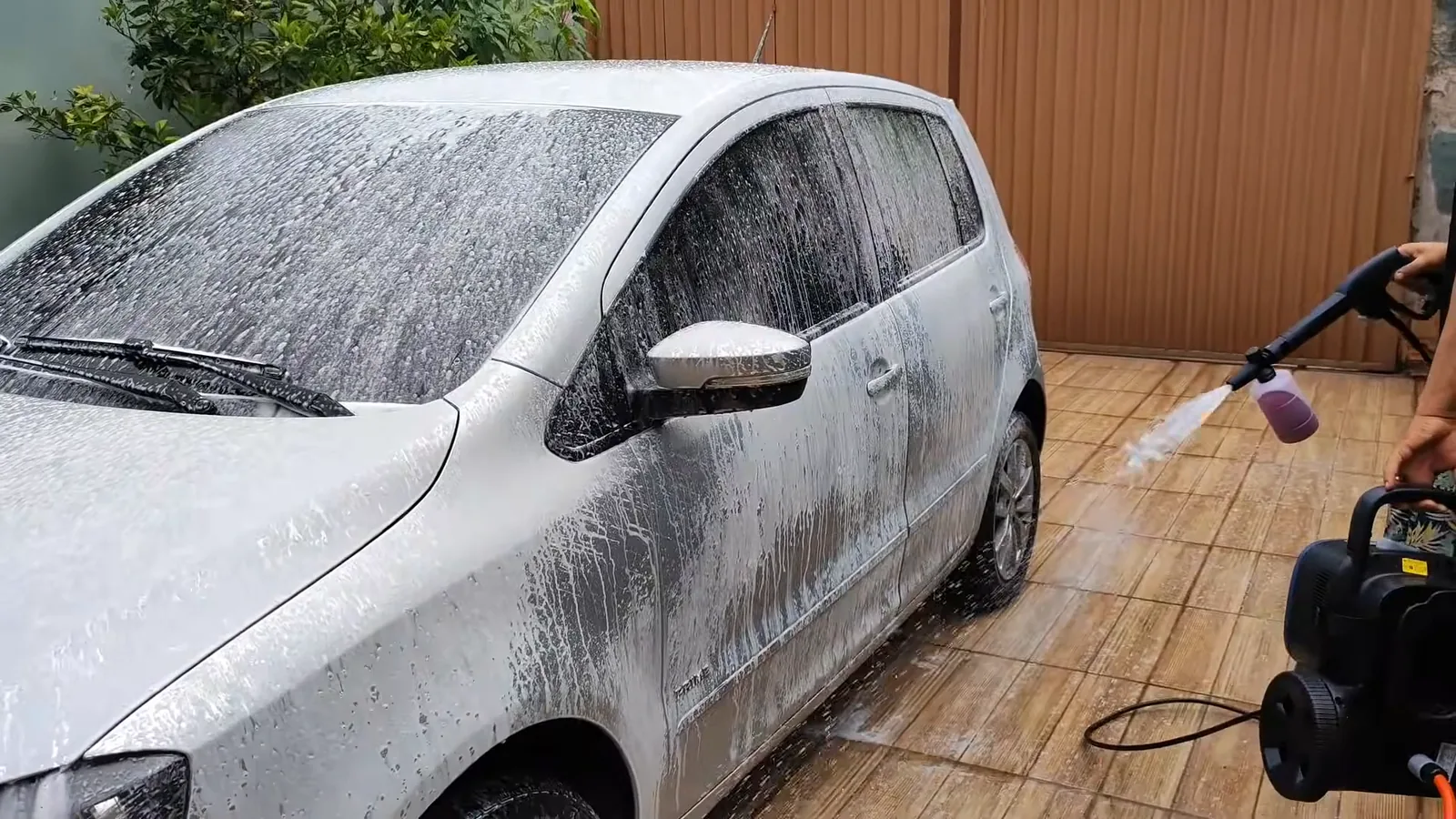 Lavadora no piso enquanto aplicador de detergente cobre o veículo