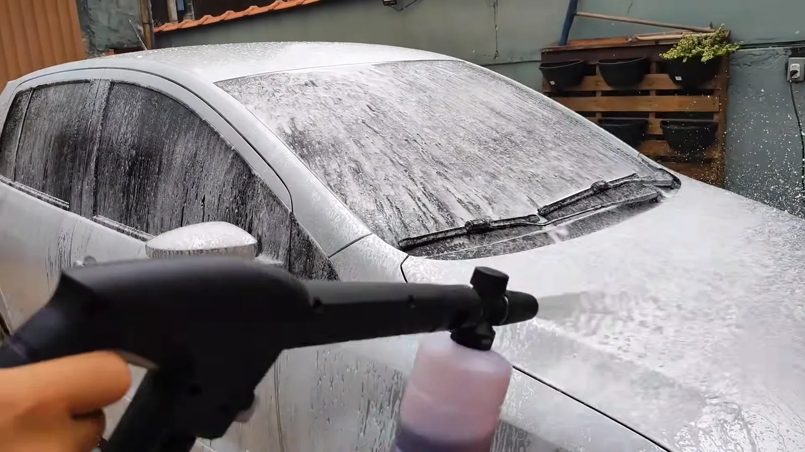 Aplicador de detergente espalhando espuma sobre o capô do carro
