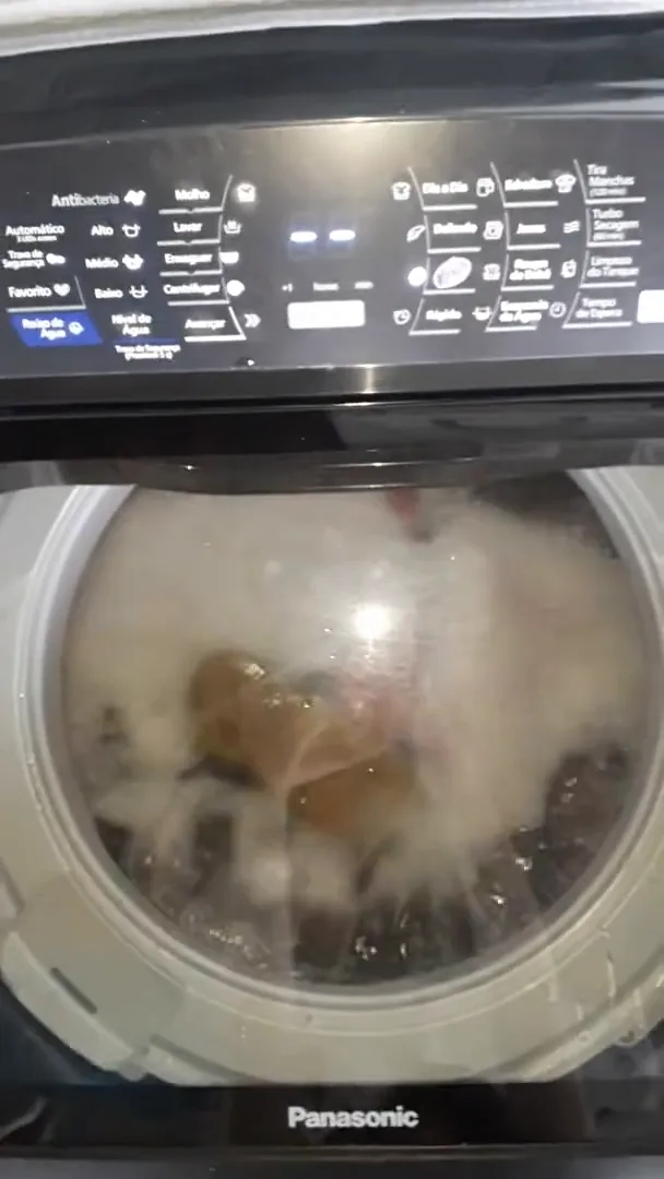 Lavadora Panasonic agitando roupas com espuma ativa visível pela tampa