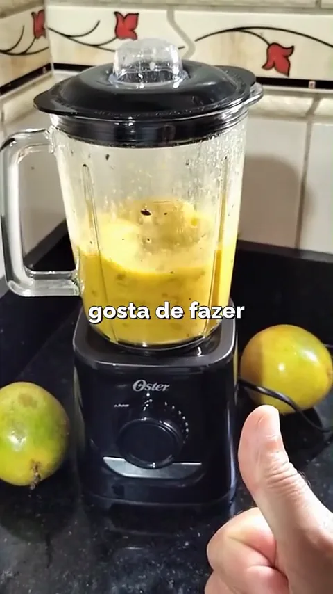 Liquidificador Oster com jarra de vidro em pleno funcionamento na bancada