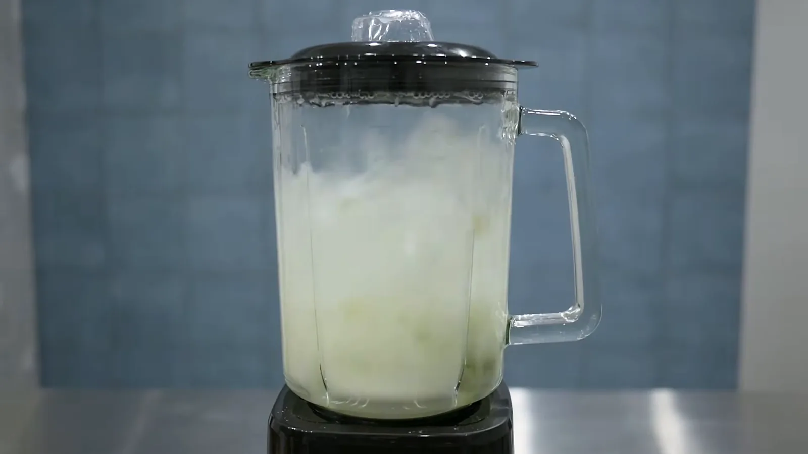 Liquidificador Oster OLIQ520 triturando folhas e água na jarra de vidro