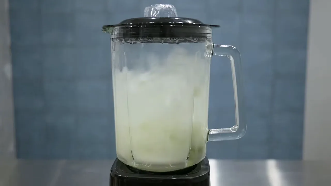 Liquidificador Oster triturando folhas verdes com água na jarra