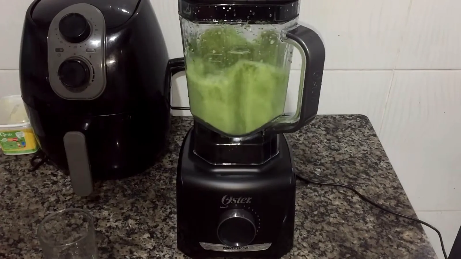 Liquidificador Oster OLIQ610 batendo ingredientes verdes na jarra plástica