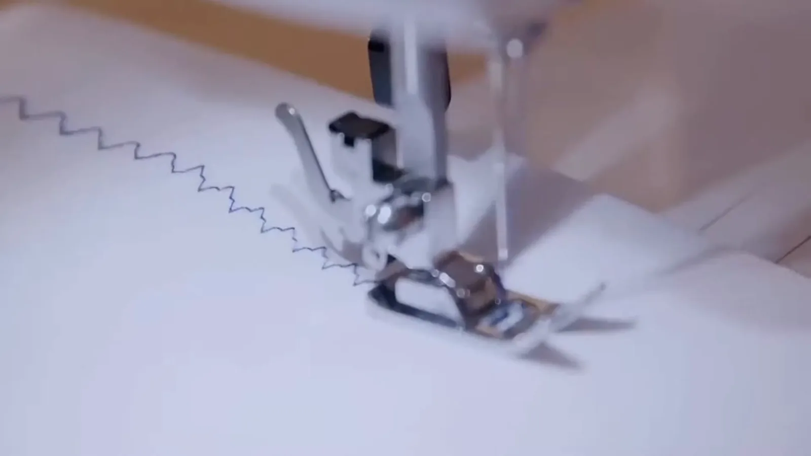 Agulha da máquina Elgin costurando ponto decorativo em tecido branco