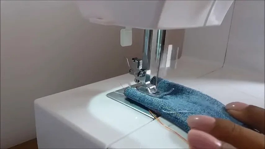Máquina mecânica realizando costura reta em camadas de jeans
